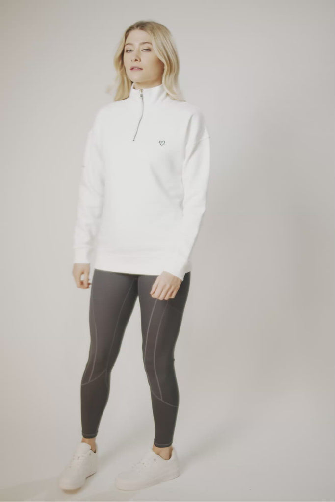 Woman wearing white half-zip sweatshirt